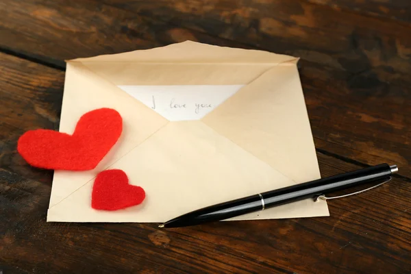 Envelope with hearts and pen on rustic wooden table background — Stock Photo, Image