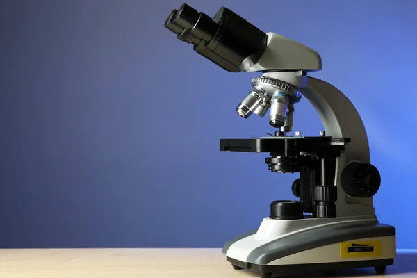 Mikroskop auf Tisch, auf farbigem Hintergrund — Stockfoto