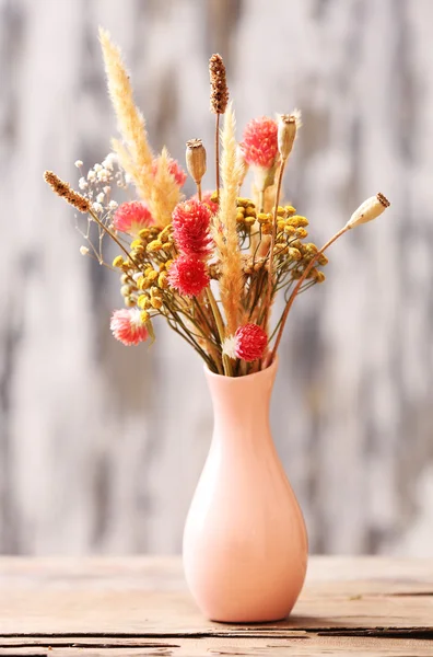 Bouquet of dried flowers in vase on bright background