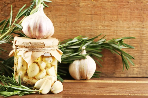 Ingeblikte knoflook in glazen pot op houten achtergrond — Stockfoto