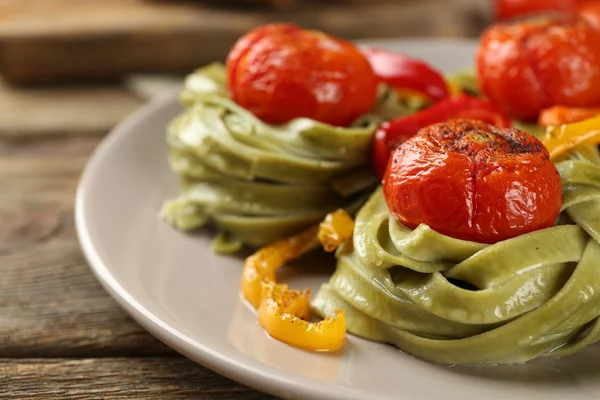Sabrosa pasta verde con pimienta, y tomates sobre fondo de mesa de madera — Foto de Stock