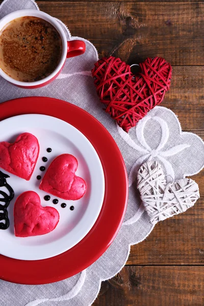 Cookies in form of heart in plate with cup of coffee on napkin, on rustic wooden planks background — Stock Photo, Image