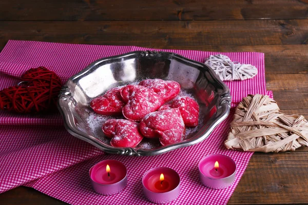 Biscotti in forma di cuore su vassoio di metallo con candele e tovaglioli su sfondo tavolo in legno rustico — Foto Stock