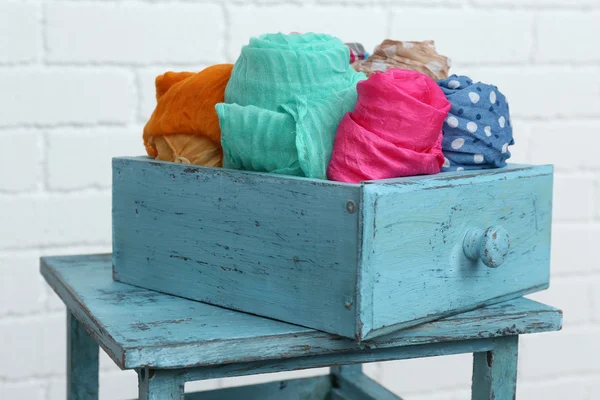 Verschillende sjaals in kleur lade op witte bakstenen muur achtergrond — Stockfoto