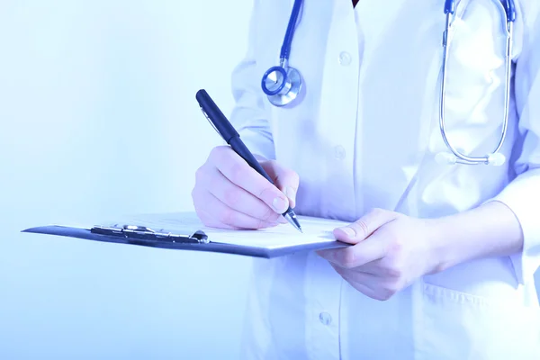 Doctor writing on clipboard on light background — Stock Photo, Image