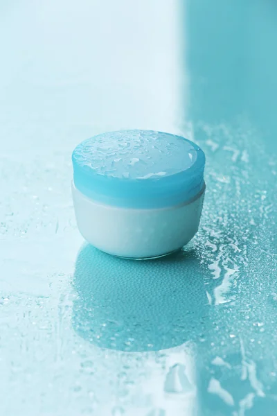 Crema cosmética sobre fondo azul con gotas de agua — Foto de Stock