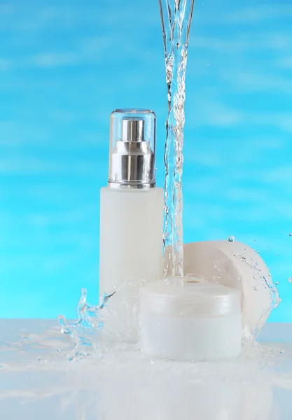 Cosmetic products in water splashes on blue background — Stock Photo, Image