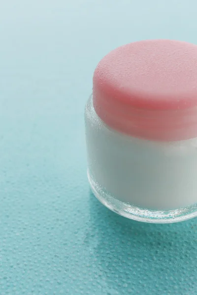 Cosmetische crème op blauwe achtergrond met water drops — Stockfoto