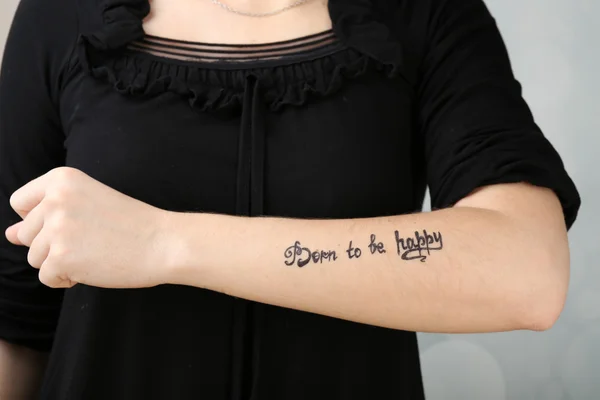 Braccio femminile con tatuaggio su sfondo chiaro — Foto Stock