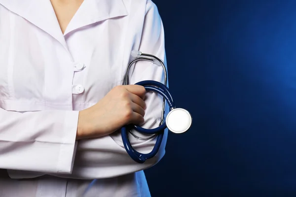 Lähikuva lääkäri käsi stetoskooppi tummansininen tausta — kuvapankkivalokuva