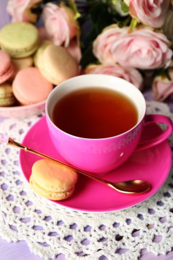 Ahşap arka plan üzerinde çay ile renkli macaroons