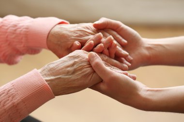 Old and young holding hands on light background, closeup clipart