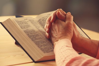 Eski İncil kadınla tablo ve koyu arka plan üzerinde eller