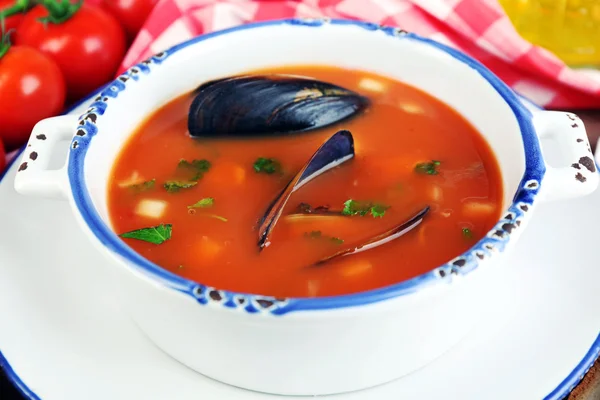 Tasty soup with mussels, tomatoes and black olives in bowl on wooden background — Stock Photo, Image