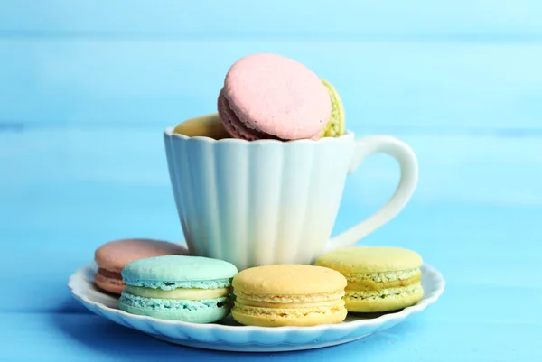 Sortiment av mjuka färgglada macaroons i färgglad mugg på färg trä bakgrund — Stockfoto