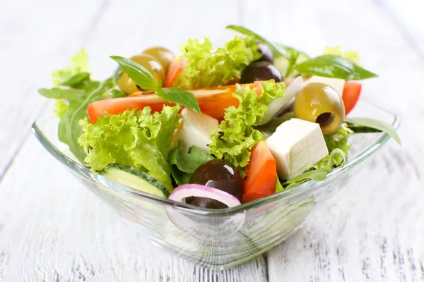 Griekse salade in glas schotel op een houten tafel achtergrond kleur — Stockfoto