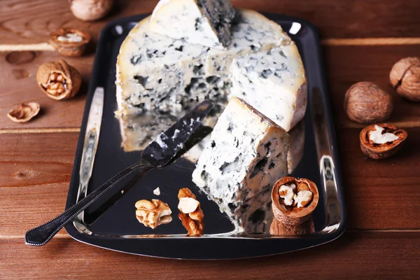 Blue cheese with nuts and blade on metal tray and wooden table background — Stock Photo, Image
