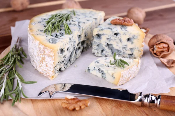 Queijo azul com raminhos de alecrim e nozes a bordo com faca e mesa de madeira fundo — Fotografia de Stock