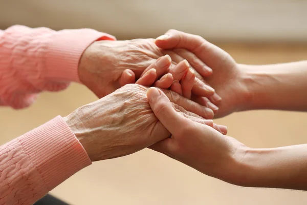 Old and young holding hands on light background, closeup — Stock Photo, Image