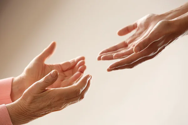 Old and young holding hands on light background, closeup — Stock Photo, Image