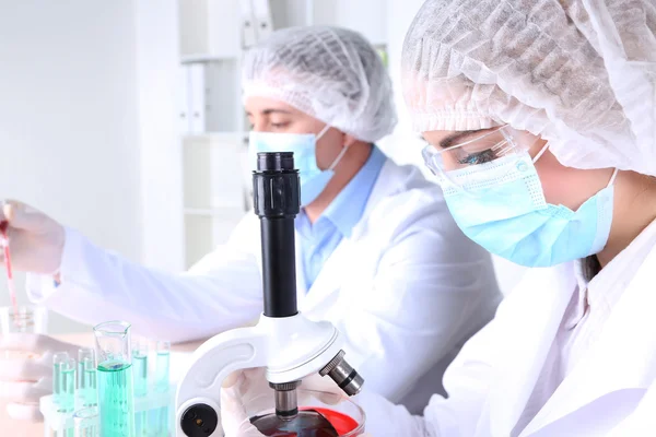 Científicos masculinos y femeninos usando microscopio en laboratorio — Foto de Stock