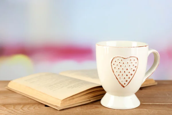 Xícara de chá e livro na mesa, no fundo brilhante — Fotografia de Stock