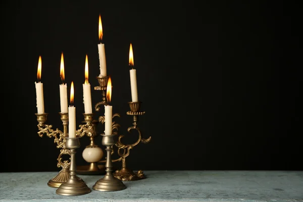 Candelabros retro con velas sobre mesa de madera, sobre fondo negro — Foto de Stock