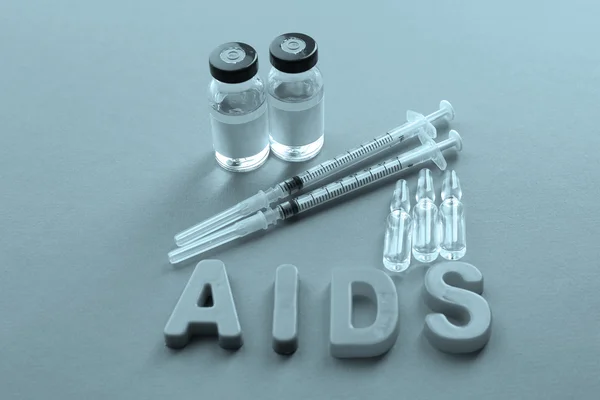 Medicamentos con palabra SIDA sobre fondo rosa — Foto de Stock