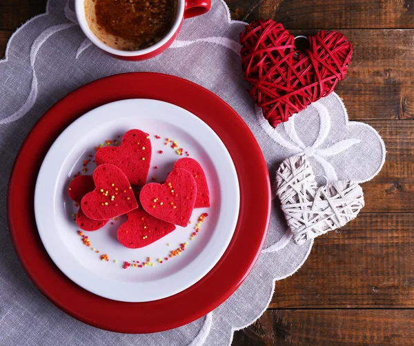 Biscuits en forme de coeur dans une assiette avec une tasse de café sur une serviette, sur des planches de bois rustiques fond — Photo