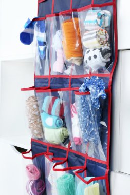 Different socks in hanging bag on closet background clipart
