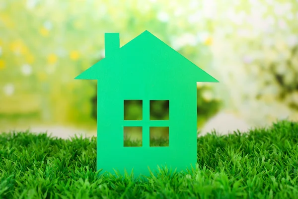 Cutout paper house on green grass and bright blurred background — Stock Photo, Image