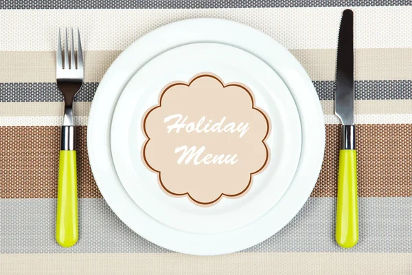 Plate with text Holiday Menu, fork and knife on tablecloth background — Stock Photo, Image