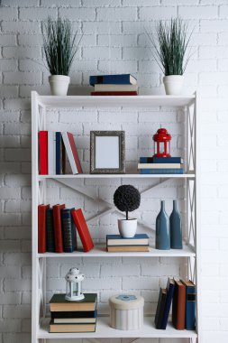 Raflardan kitapları ve tuğla duvar arka plan üzerinde dekoratif objeler ile