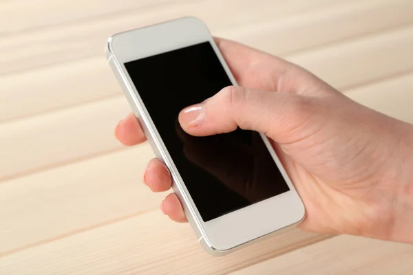 Hand met behulp van slimme mobiele telefoon op houten tafel achtergrond — Stockfoto