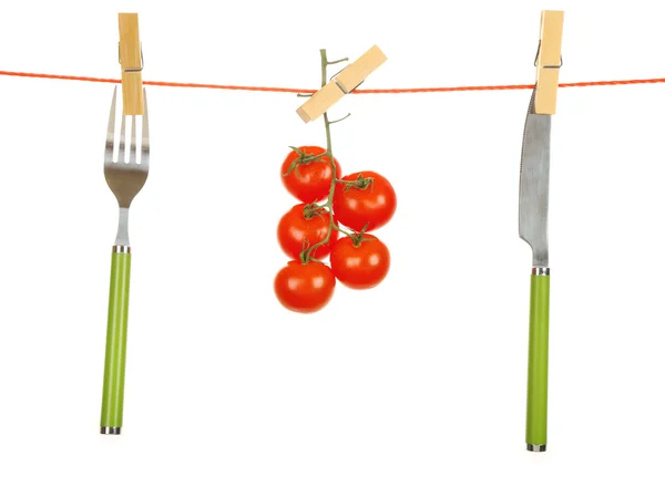 Vidlička, nůž a zralé červené rajčat visí z prádelní izolovaných na bílém pozadí — Stock fotografie