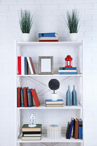 Bookshelves with books and decorative objects on brick wall background