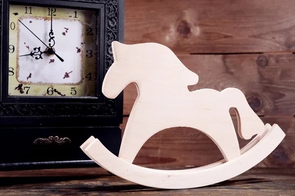 Relógio retrô com cavalo decorativo na mesa sobre fundo de madeira — Fotografia de Stock