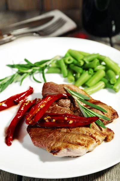 Steak with vegetables on plate on table close up — Stock Photo, Image