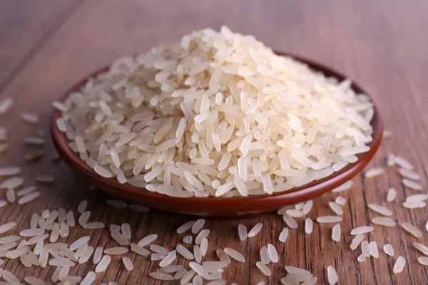 Grano de arroz en plato sobre fondo de madera — Foto de Stock