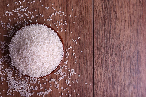 Grano de arroz en plato sobre fondo de madera — Foto de Stock