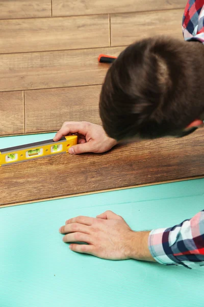 Trabalhador de carpinteiro instalando piso laminado — Fotografia de Stock