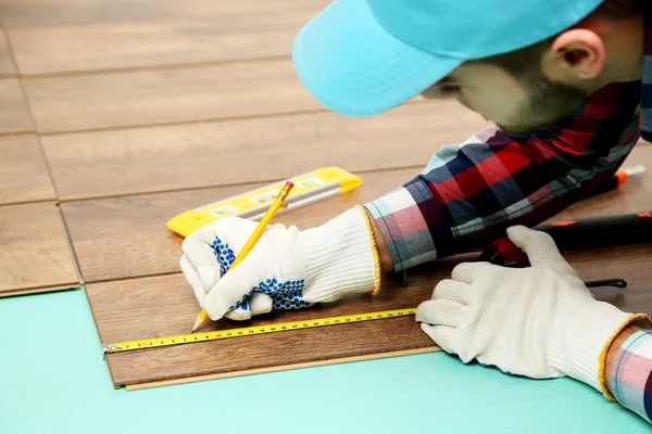 Trabalhador de carpinteiro instalando piso laminado — Fotografia de Stock