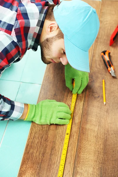 Trabalhador de carpinteiro instalando piso laminado — Fotografia de Stock