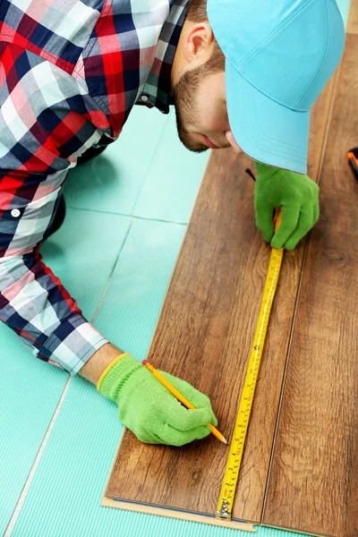 Timmerman installeert laminaat vloeren in de kamer — Stockfoto