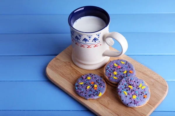 三杯牛奶上切割板和彩色木板背景釉面的饼干 — 图库照片