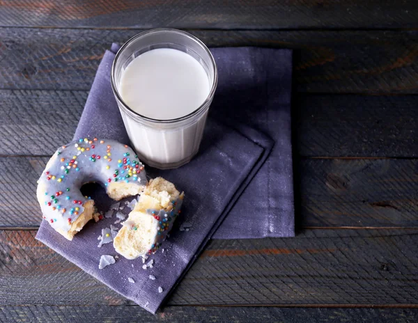 Donut crrumbled no guardanapo com vidro de leite em tábuas de madeira rústica fundo — Fotografia de Stock