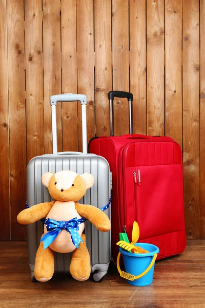 Suitcases with teddy bear and child toys on wooden planks background — Stock Photo, Image