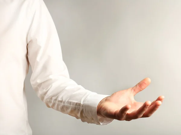 Empresario mostrando cualquier cosa sobre fondo gris — Foto de Stock