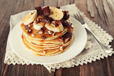 Çikolata, bal, fındık ve dilim muz plaka üzerinde ve ahşap masa arka plan üzerinde peçete ile lezzetli gözleme yığını