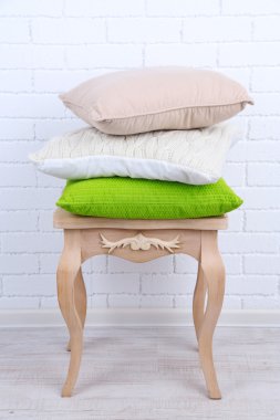 Yastıklar küçük ahşap masa ve beyaz tuğla duvar arka plan